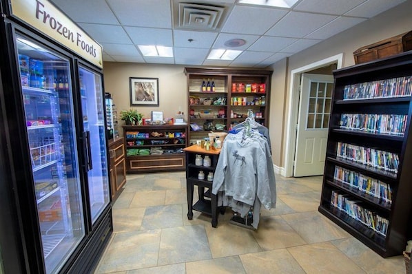 A grocery store interior with frozen foods, a clothing rack, and a bookshelf.