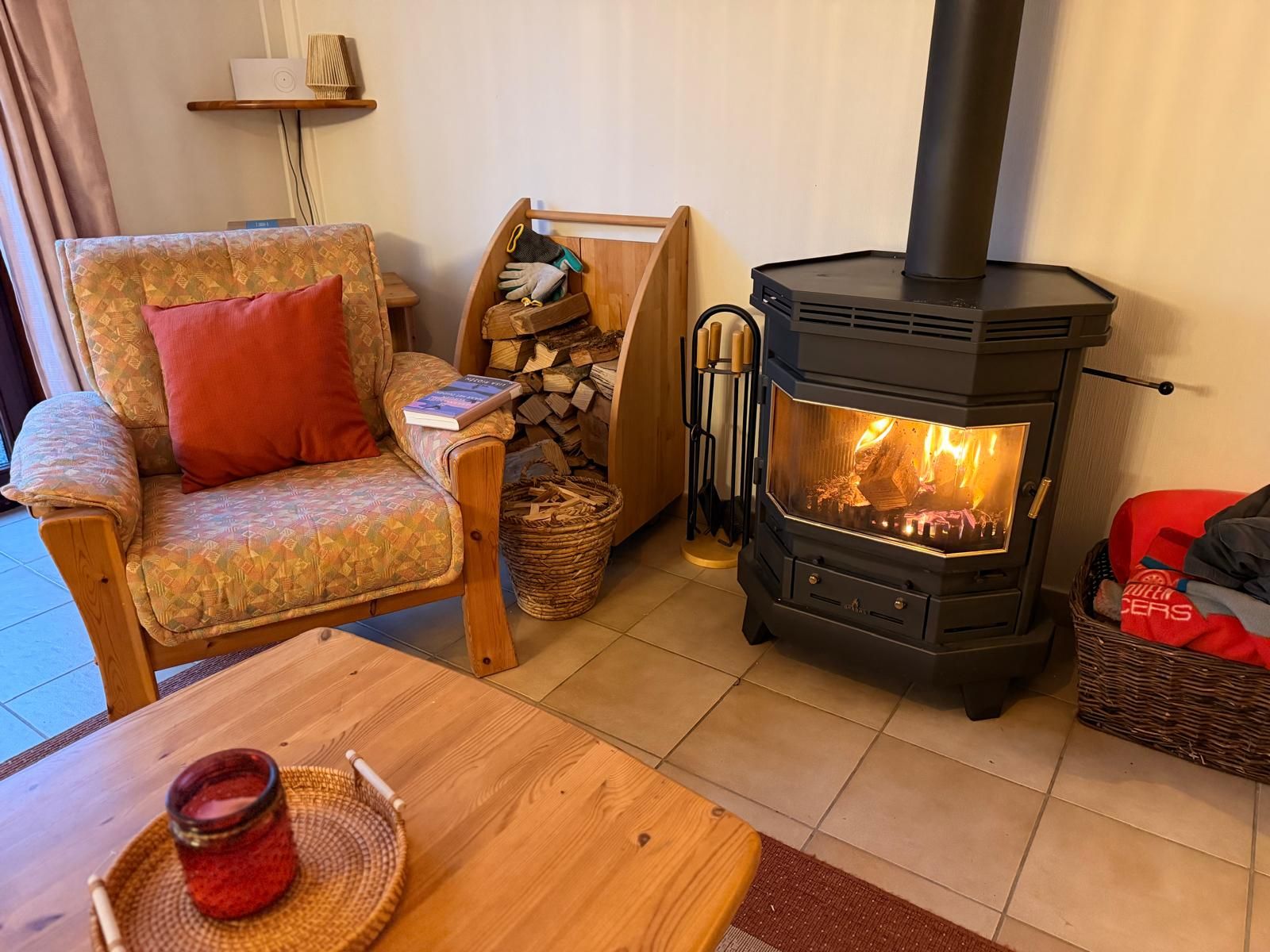 Ein gemütliches Wohnzimmer mit einer Couch, einem Tisch mit einer Kerze und einem Kaminofen.