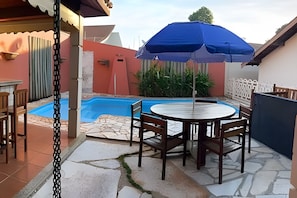 Un patio con piscina, una mesa y sillas.