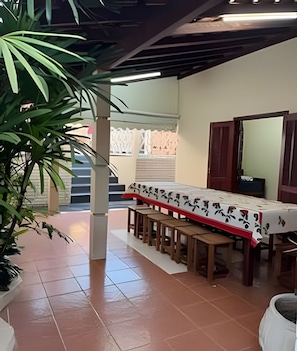 Un comedor con una mesa preparada para cuatro, bancos, una planta en maceta y una escalera que sube a un nivel superior.