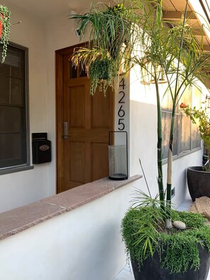 A hotel entrance with a wooden door, a mailbox, a potted plant, and a number sign. - Bright 2BR with Chef's Kitchen near Sony Studios (Culver City)