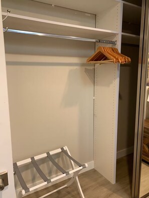A walk-in closet with a metal rack, wooden hangers, and a white shelf unit. - Bright 2BR with Chef's Kitchen near Sony Studios (Culver City)