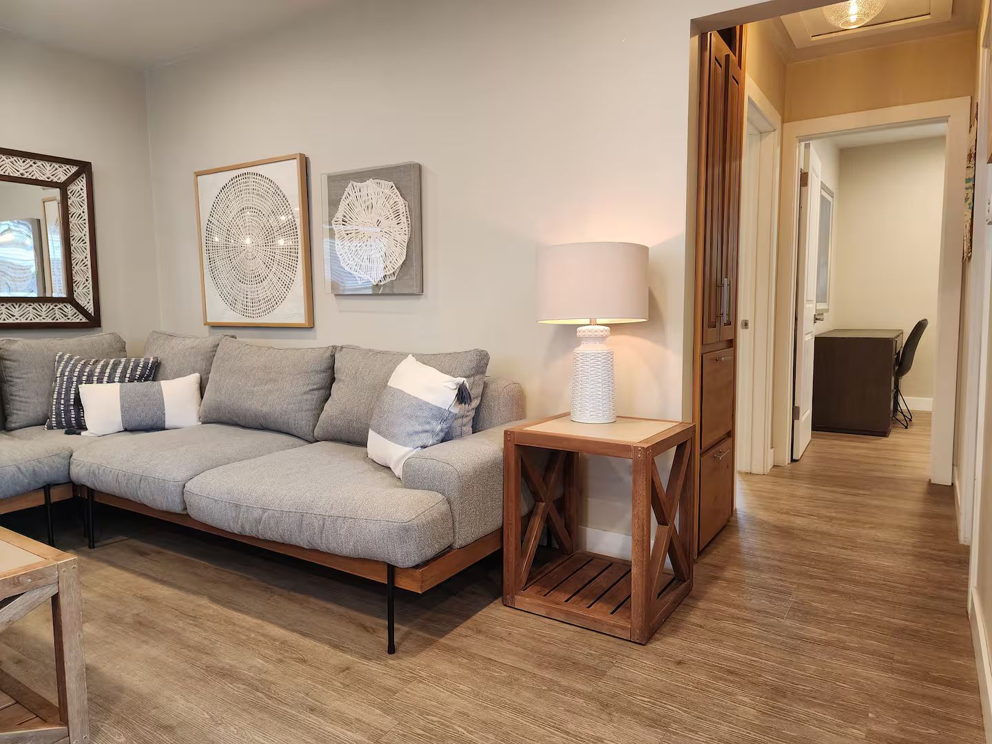 Un salon moderne avec un canapé d’angle, une table basse en bois et une lampe.