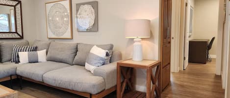 Un salon moderne avec un canapé d’angle, une table basse en bois et une lampe.