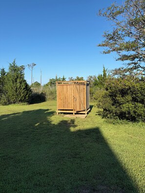 A wooden shed in a grassy area with trees and bushes around. - Remote tiny home/loft overlooking the Roanoke Sound & the Outer Banks (Manns Harbor)
