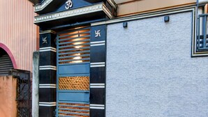 A building entrance with a decorative gate featuring horizontal slats and a textured panel. - Deluxe Shyam Bazar Guest House (Kolkata)