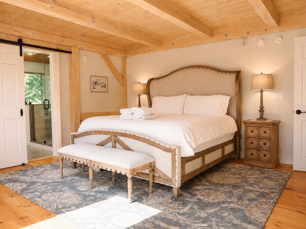 Ein Schlafzimmer mit Bett, Sitzbank, Nachttisch und einer Tür, die auf einen Balkon führt.