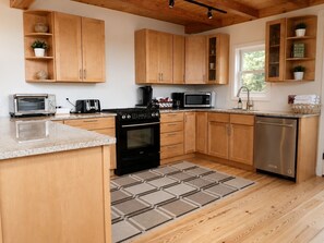 A kitchen with wooden cabinets, a stove, a microwave, and a dishwasher. - Slopeside Estate Guesthouse: Hot tub, AC, Grill (Killington)