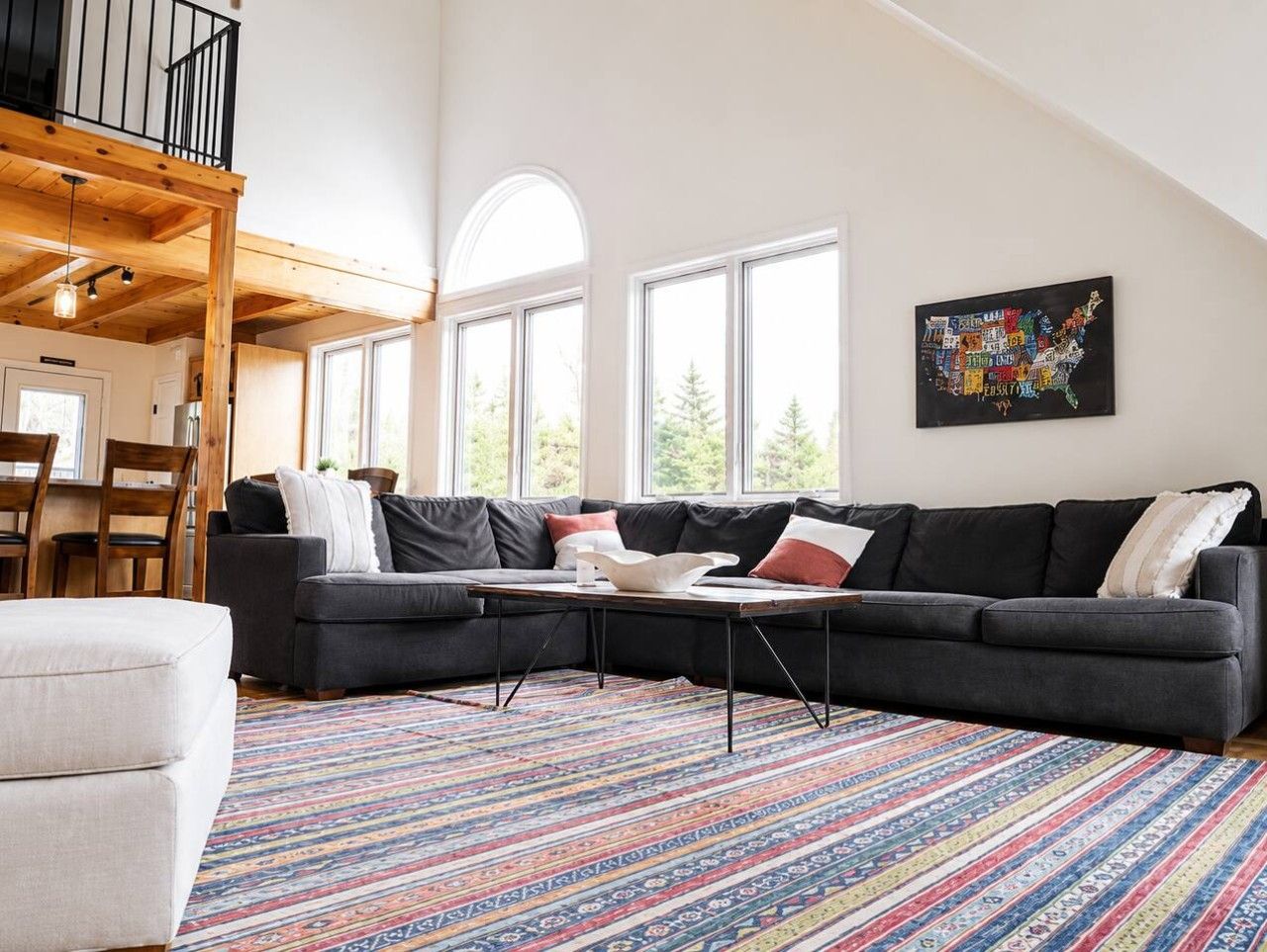 Een moderne woonkamer met een hoekbank, een salontafel en een kleurrijk vloerkleed.