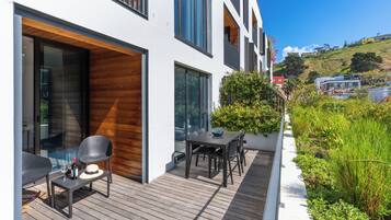 A modern house with a wooden deck, outdoor seating, and a view of the surrounding landscape.