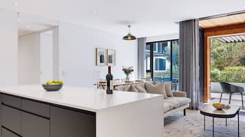 A modern kitchen with a central island, dining area with a sofa and chairs, and a view of the outdoors.