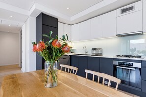 Una cocina moderna con comedor, que incluye una mesa de madera, sillas y un jarrón con flores.