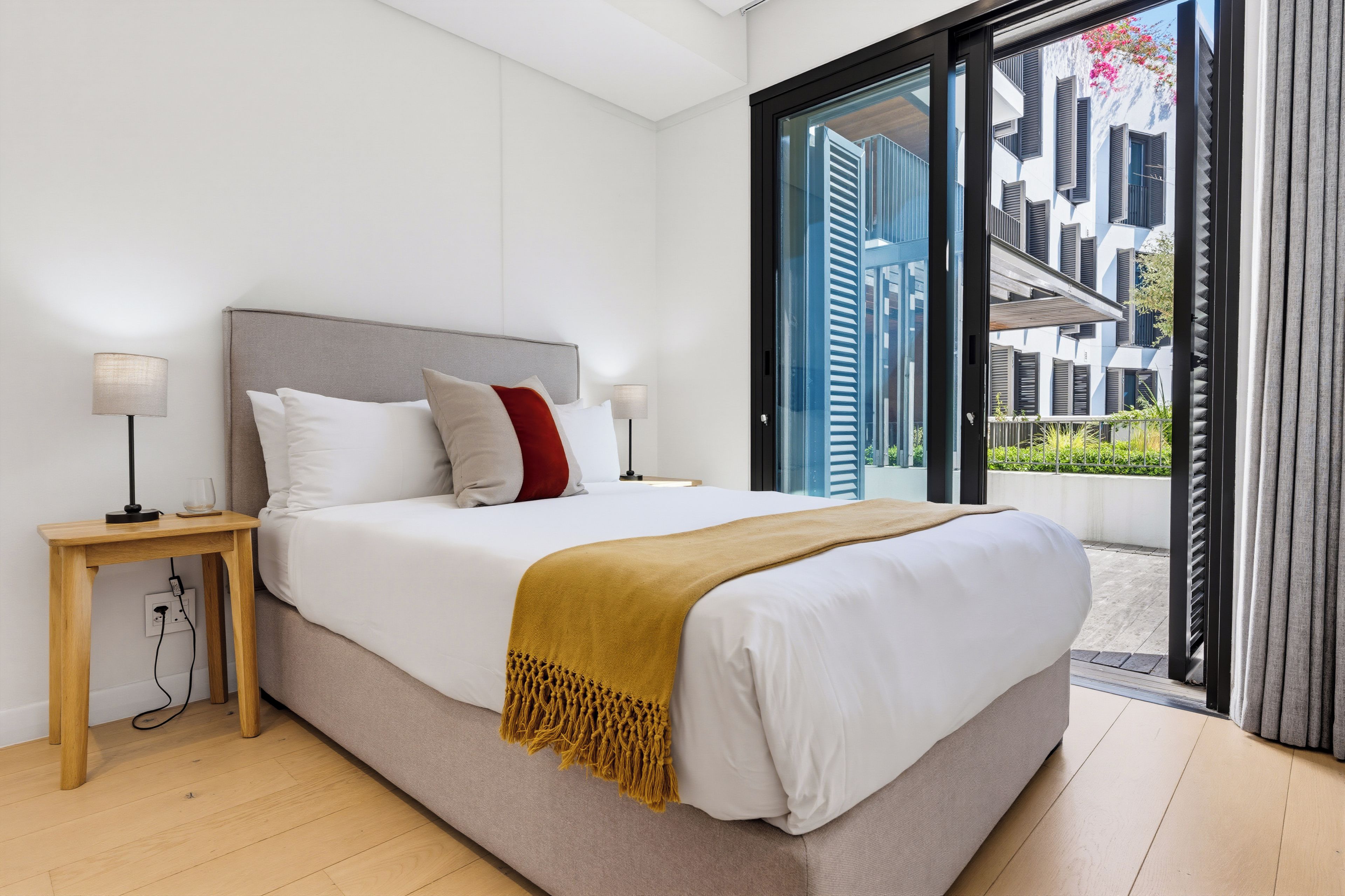 Un dormitorio moderno con una cama grande, lámparas de noche y vistas al exterior.