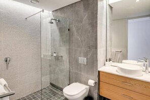Ein modernes Badezimmer mit einer gläsernen Duschkabine, einer Toilette und einem Waschtisch mit zwei Waschbecken.