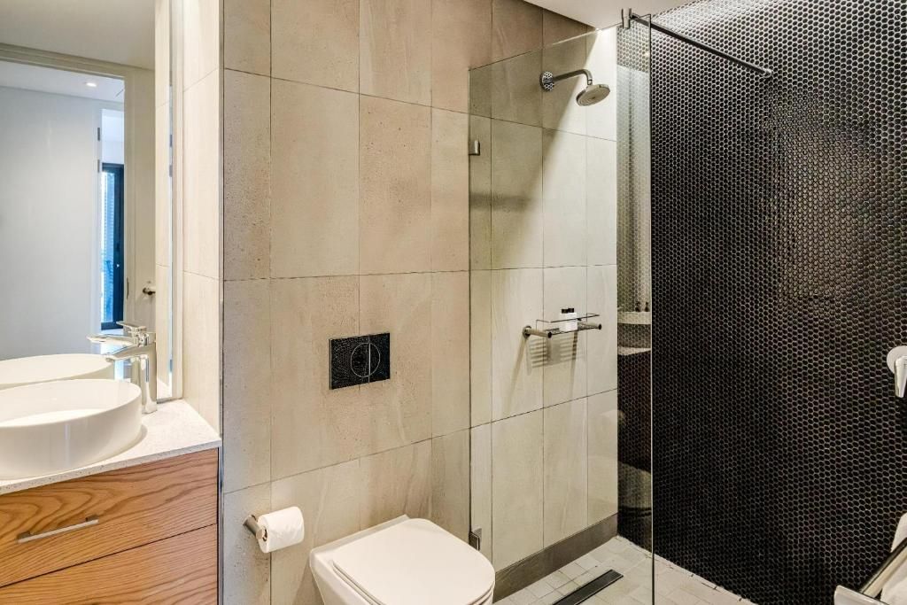 Une salle de bain comprenant des toilettes, un lavabo et un espace douche.