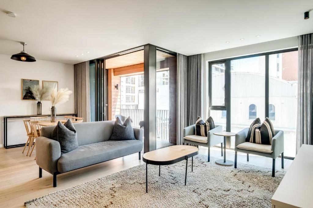 Een moderne woonkamer met een bank, fauteuils, een salontafel en een eethoek met stoelen.