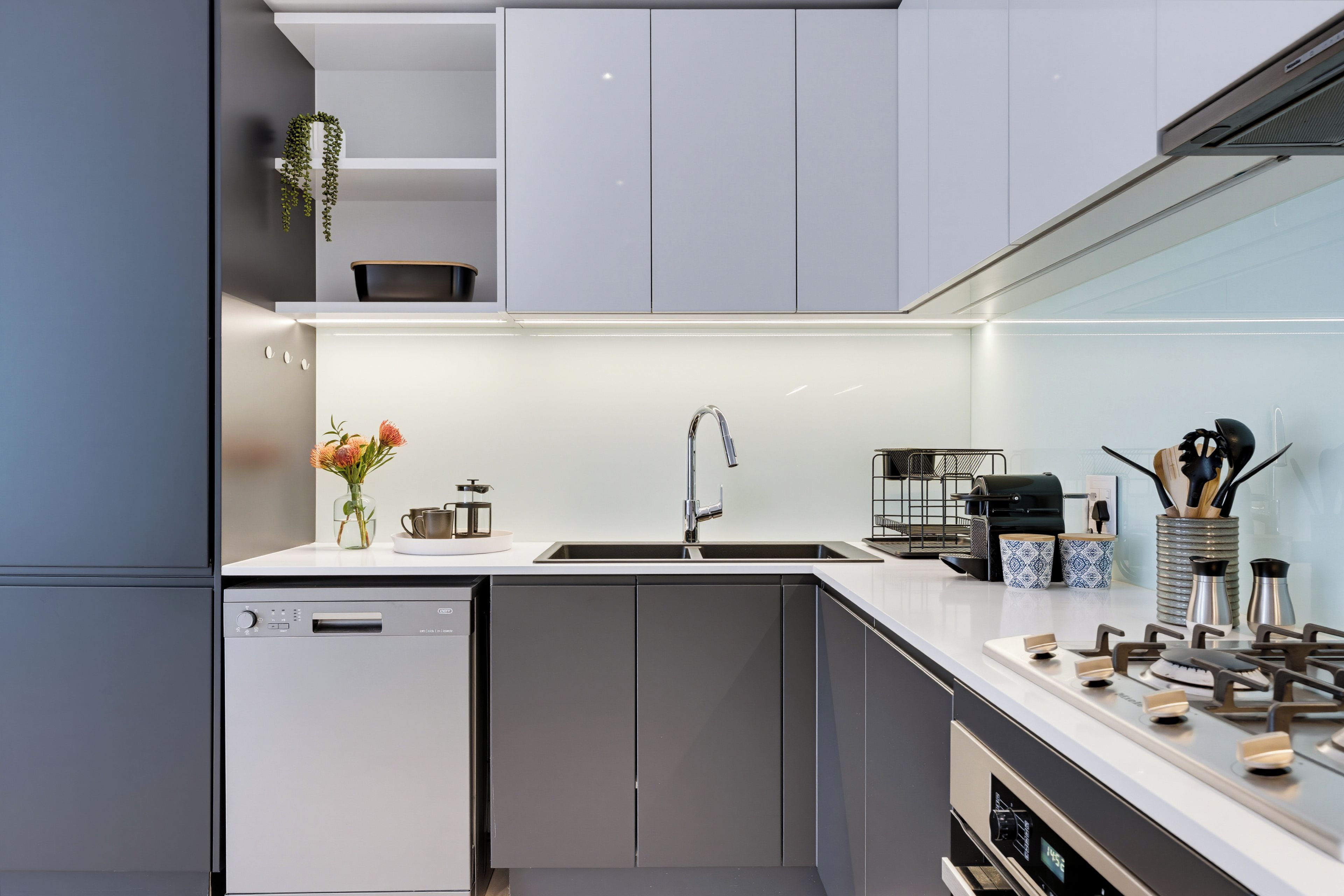 A modern kitchen with a dishwasher, sink, and stove.
