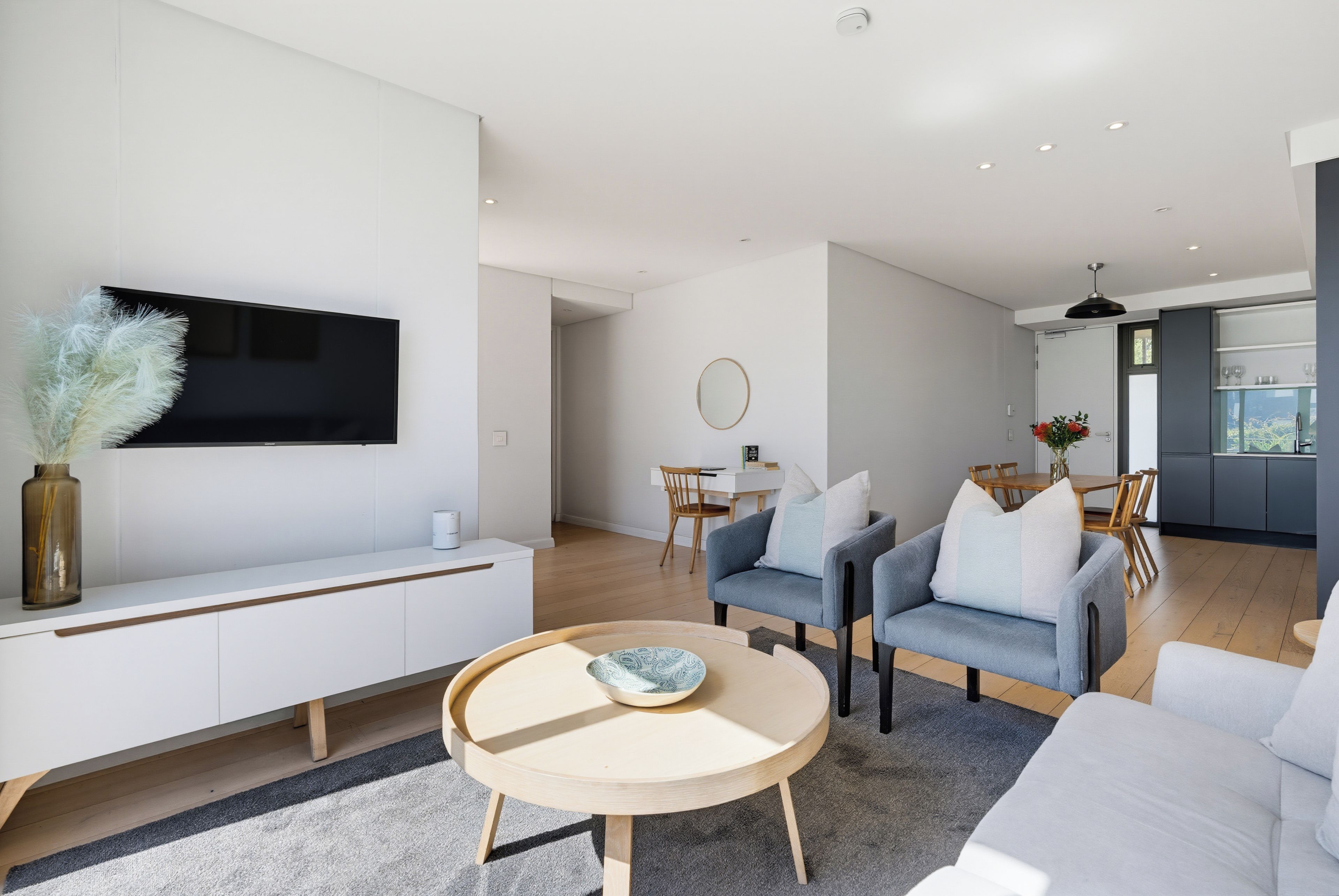 Un salon moderne doté d’un téléviseur à écran plat, d’un canapé, d’une table basse et d’un coin repas avec une table et des chaises.