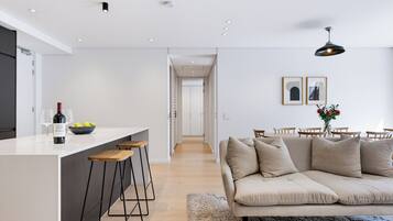 Cocina moderna con una isla central, taburetes de bar y una zona de comedor con sofá y sillas.