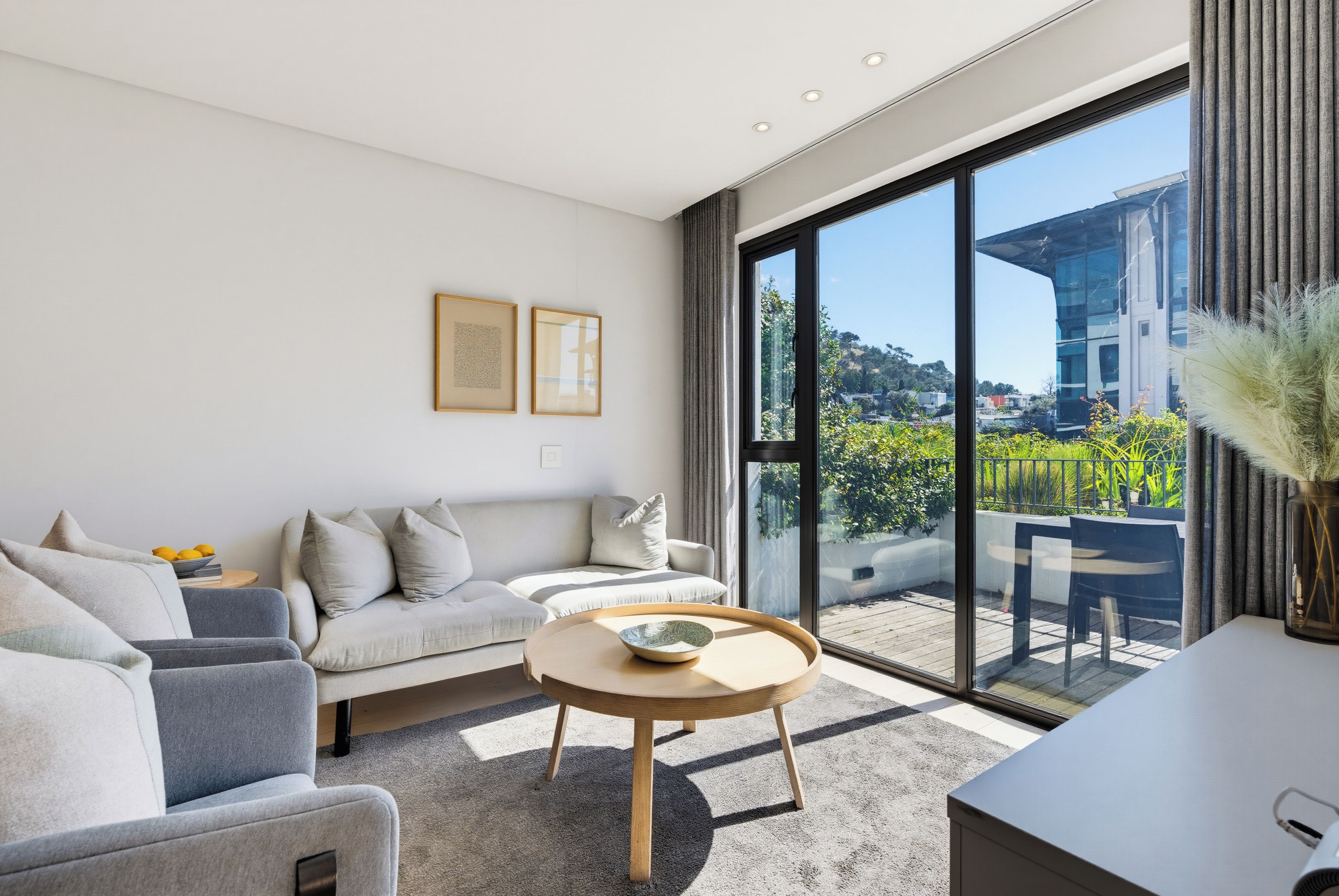 A modern living room with a sofa, a coffee table, and a view of a balcony.