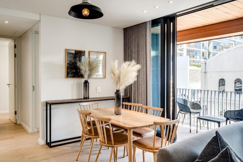A modern interior with a dining area, a sofa, and a balcony with outdoor seating.
