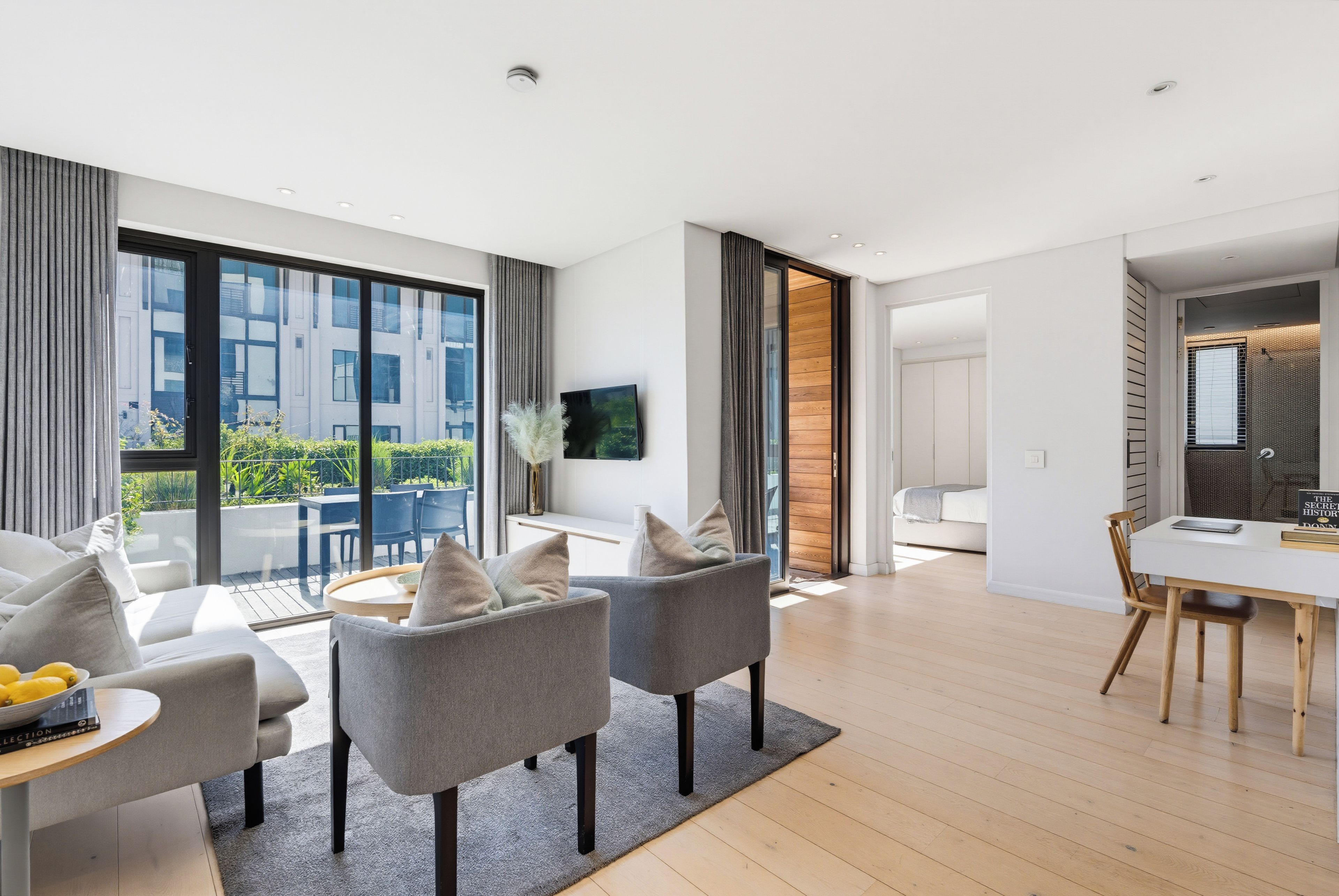 Una sala moderna con un conjunto de sofás, una mesa de comedor y un televisor montado en la pared.