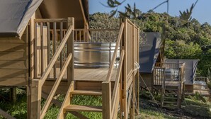 Une terrasse en bois avec une chaise en métal, un baril en métal et un espace abrité.
