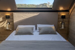A room with a bed, two bedside tables, and a skylight. - Glamping Pagliaini (Riparbella)