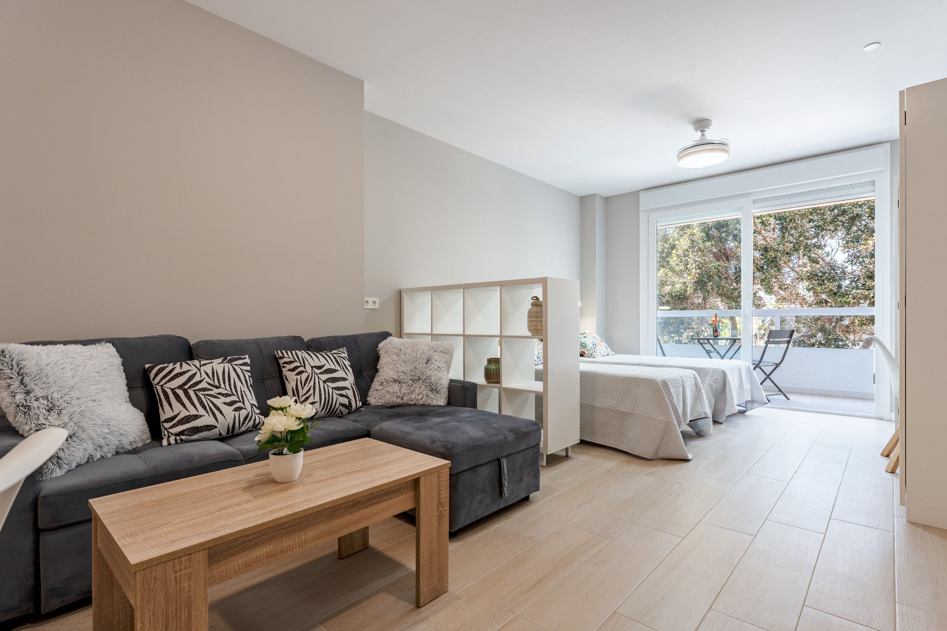 Un salon moderne avec un canapé, une table basse et une vue sur l’extérieur grâce à de grandes fenêtres.