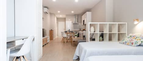 A modern, well-lit bedroom with a bed, bedside tables, and a large window.