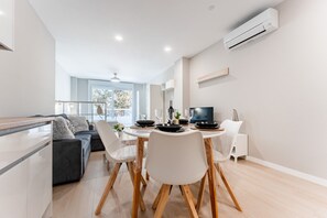 Een moderne keuken met een eethoek, witte meubels en een airconditioning.