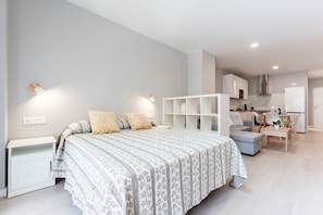 A modern bedroom with a bed, bedside tables, and a built-in shelving unit. - MalagaSuite Urban Beach D (Torremolinos)