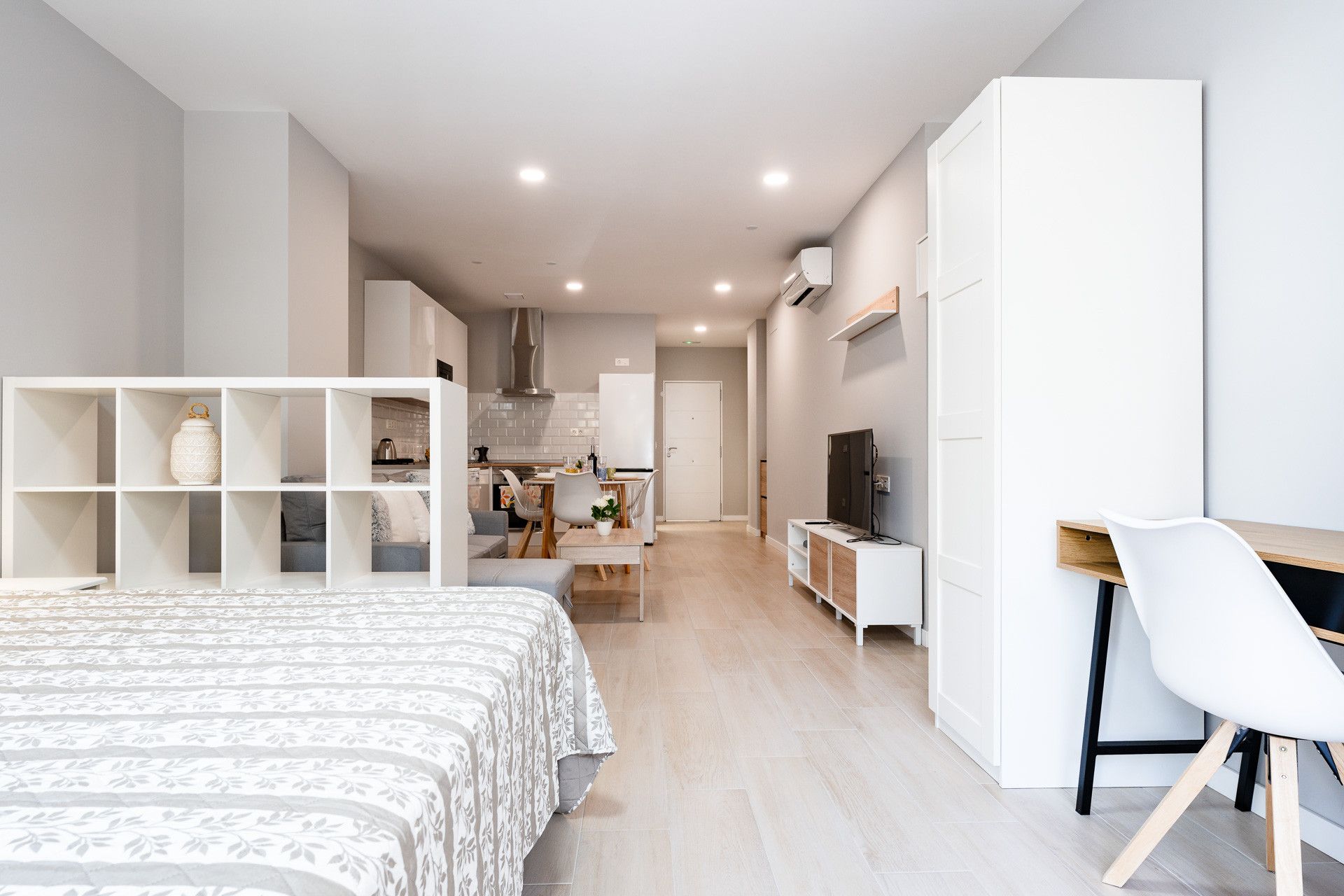 Une chambre moderne et bien éclairée, équipée d’un lit, d’un bureau et d’une télévision.