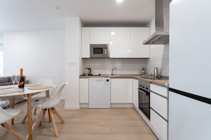 A modern kitchen with white cabinetry, a built-in microwave, a dishwasher, and a stove. - MalagaSuite Urban Beach E (Torremolinos)