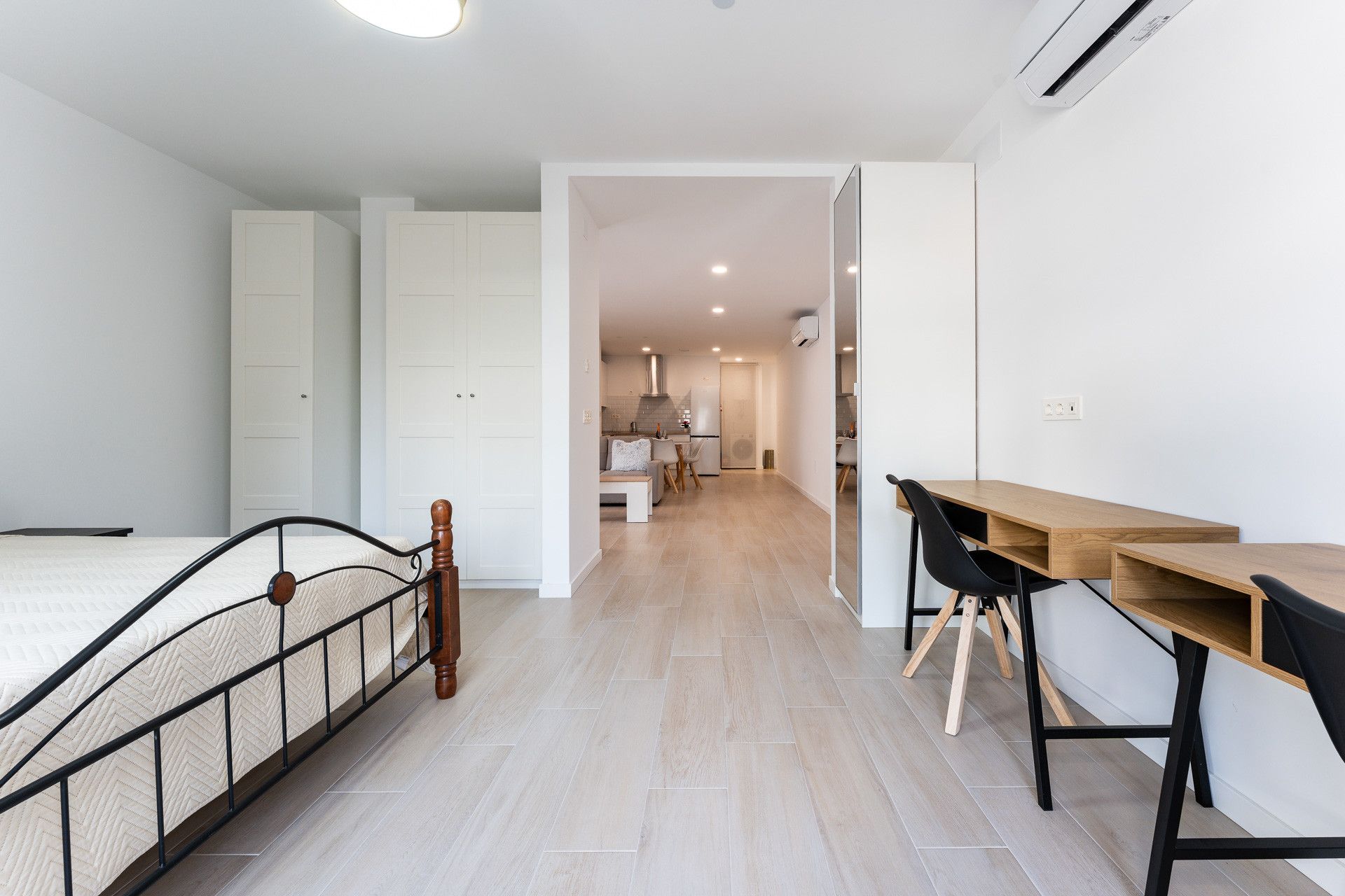 Un appartement moderne comprenant un lit, un bureau en bois et une kitchenette.