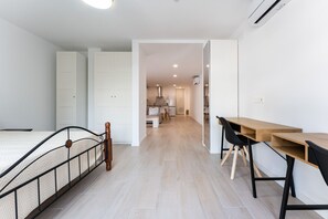 Ein modernes Apartment mit einem Bett, einem Holztisch und einer Küchenzeile.