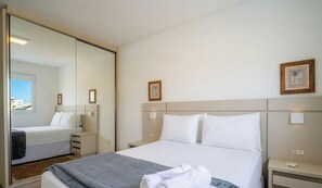 A hotel room with a bed, bedside tables, a mirror, and a window. - Apt. w/ Jacuzzi in Condo. w/ Pool Cmn0304 (Florianópolis)