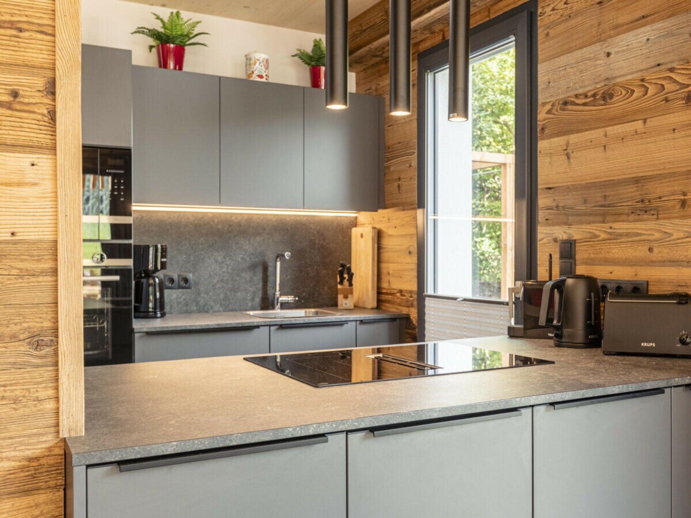 A modern kitchen with a central island, built-in appliances, and wooden accents.