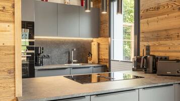 A modern kitchen with a central island, built-in appliances, and wooden accents.