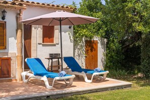 Een terras met twee loungestoelen, een tafel en een parasol.