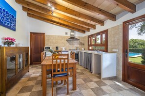 Een keuken met een houten tafel, een inbouwoven en uitzicht op een zwembad.