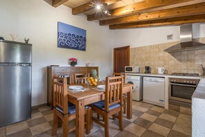 Eine Küche mit einem Holztisch, Stühlen, einem Kühlschrank, einer Mikrowelle, einem Geschirrspüler und einem Herd.