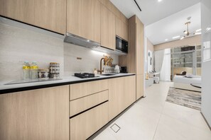A modern kitchen with a microwave, stove, and sink. - Luxury Top-Floor Studio in JVC with Panoramic Terrace (JVC)