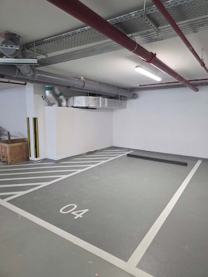 A parking garage with marked parking spaces, including space number 04, and visible HVAC ductwork on the ceiling. - Luxury Top-Floor Studio in JVC with Panoramic Terrace (JVC)