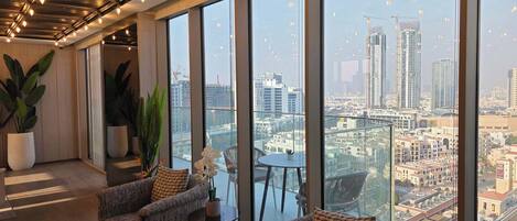 A high-rise interior with large windows, two sofas, a small table, and potted plants.