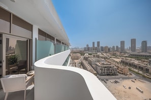 A modern building with a curved balcony overlooking a cityscape. - Luxury Top-Floor Studio in JVC with Panoramic Terrace (JVC)