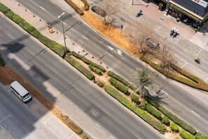 Une route à voies multiples avec un terre-plein central, un passage piéton et un bâtiment commercial doté d’une terrasse.