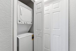 A laundry room with a washer and dryer, a door, and a textured wall. - 4BR townhouse at Regal Oaks (Kissimmee)