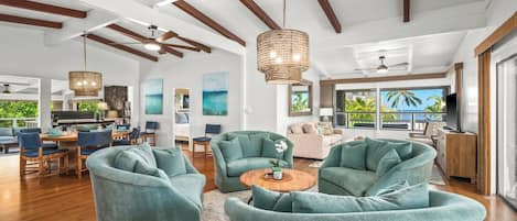 A spacious living area with teal armchairs, a wooden coffee table, and a large window offering a view of the outdoors.
