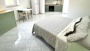 A compact bedroom with a bed, a small desk, and a kitchenette in the background. - Verde Salvia Home - Vacation Rental in Frascati (Frascati)